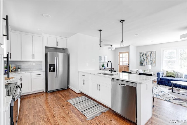 kitchen with stainless steel appliances, a sink, a peninsula, and light wood finished floors