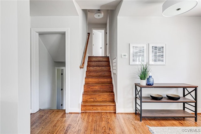 stairway with wood finished floors and baseboards