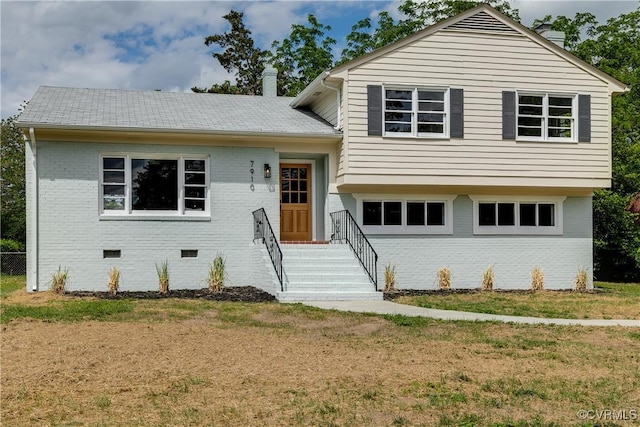 tri-level home with brick siding, crawl space, a chimney, and a front yard