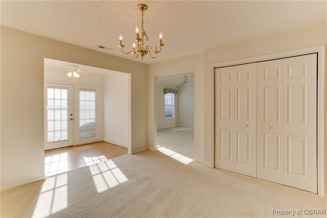 unfurnished dining area featuring light colored carpet, a chandelier, a textured ceiling, a ceiling fan, and baseboards