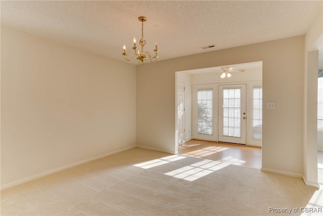 unfurnished room with light colored carpet, a chandelier, baseboards, a textured ceiling, and a ceiling fan