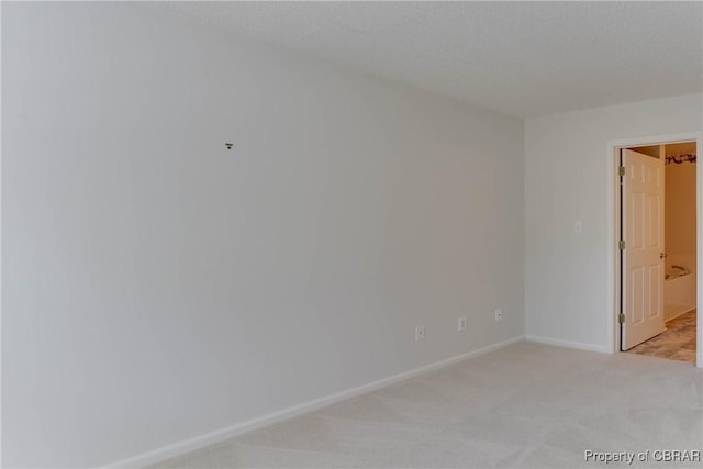 unfurnished room with light carpet and baseboards