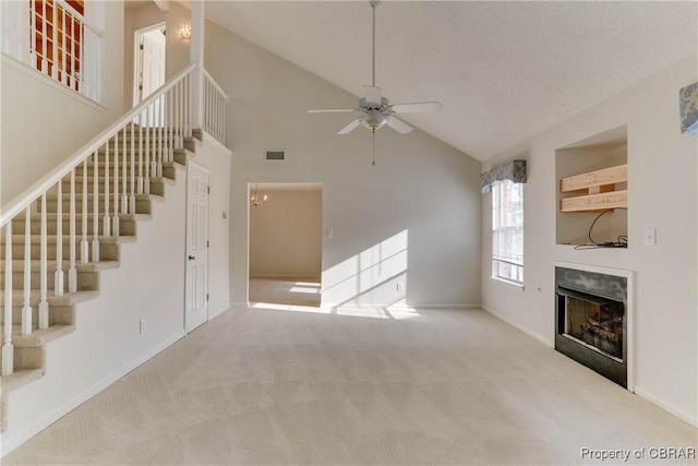 unfurnished living room featuring stairway, high vaulted ceiling, carpet floors, a ceiling fan, and a fireplace