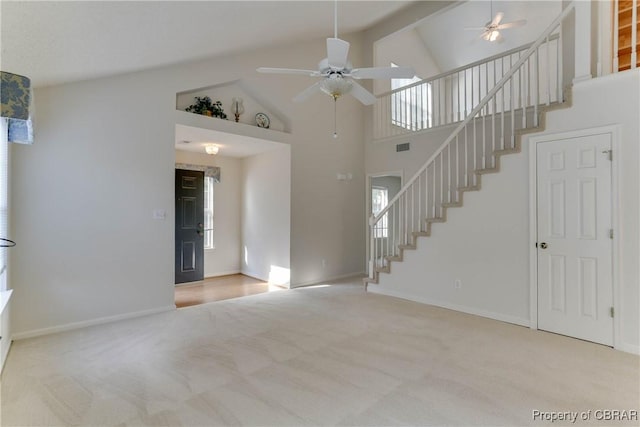unfurnished living room with high vaulted ceiling, ceiling fan, stairs, carpet floors, and baseboards