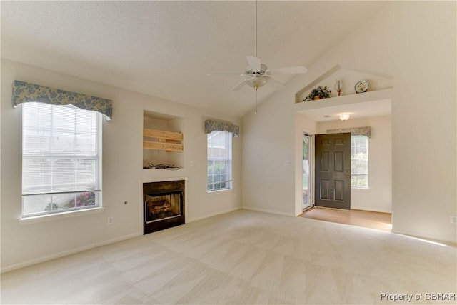unfurnished living room with a ceiling fan, healthy amount of natural light, carpet flooring, a fireplace, and lofted ceiling