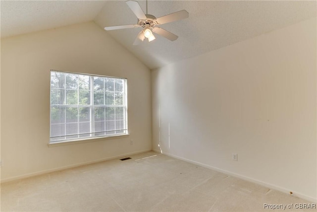 carpeted spare room featuring lofted ceiling, a ceiling fan, and baseboards