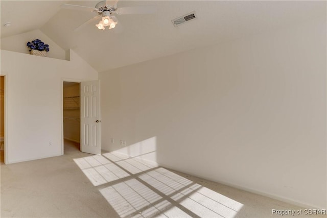 unfurnished bedroom featuring carpet flooring, vaulted ceiling, a spacious closet, ceiling fan, and a closet