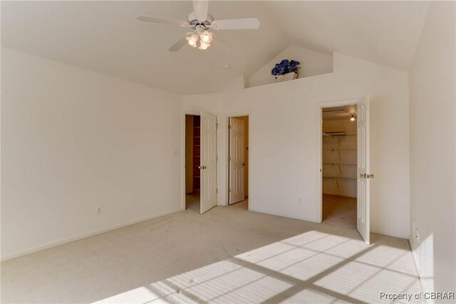unfurnished bedroom with carpet flooring, a walk in closet, high vaulted ceiling, and ceiling fan