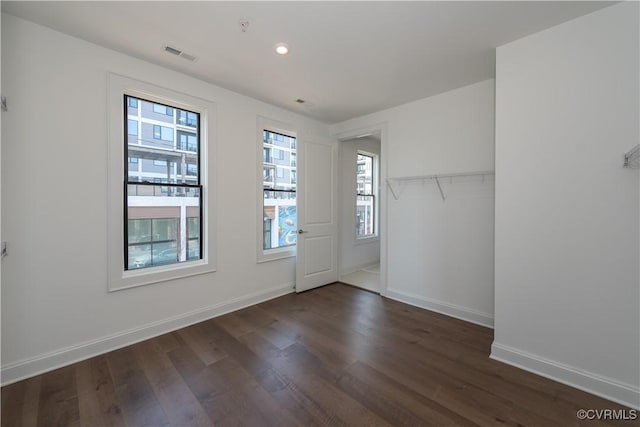 unfurnished bedroom featuring dark wood-type flooring, baseboards, recessed lighting, and a closet