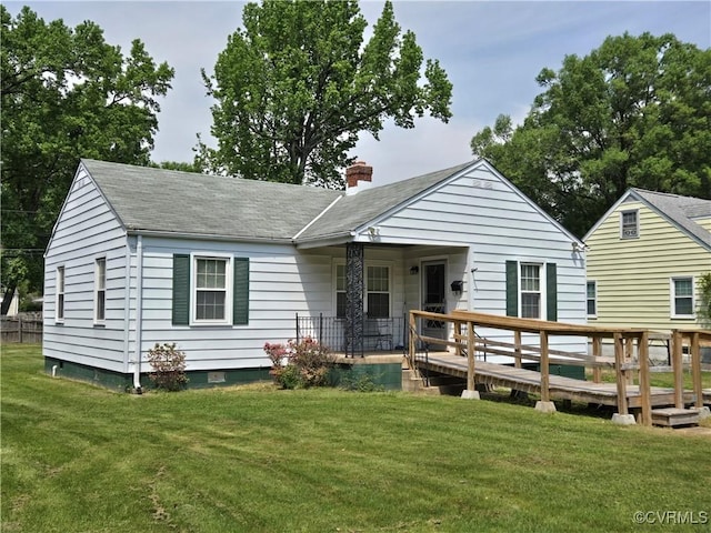 view of front of home featuring roof with shingles, a chimney, a front lawn, and a wooden deck