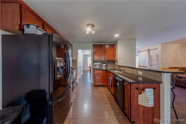 5631 Buckhunt Ln, New Kent, VA 23124 - kitchen with black appliances, a kitchen bar, wood finished floors, decorative backsplash, and a barn door