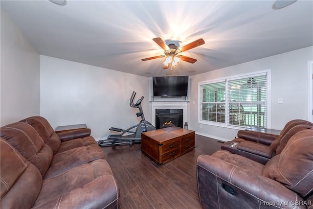 5631 Buckhunt Ln, New Kent, VA 23124 - living area featuring dark wood-style flooring, a ceiling fan, a lit fireplace, and baseboards
