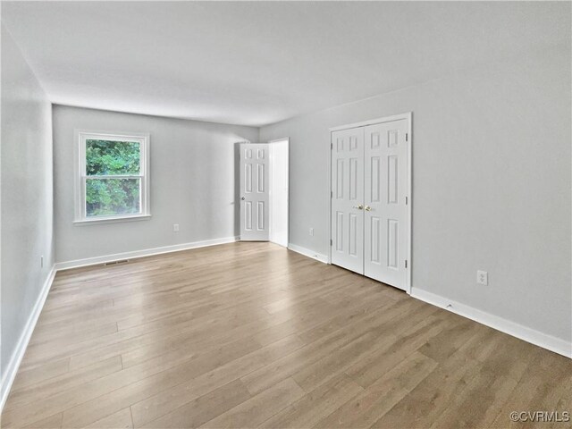 unfurnished bedroom with wood finished floors, baseboards, and a closet