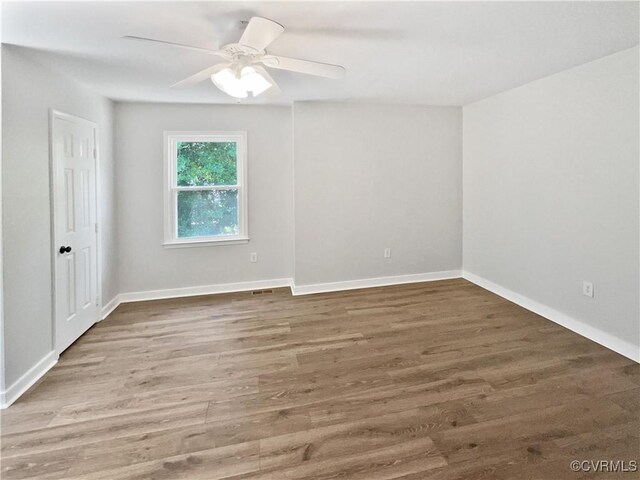unfurnished room with wood finished floors, a ceiling fan, and baseboards