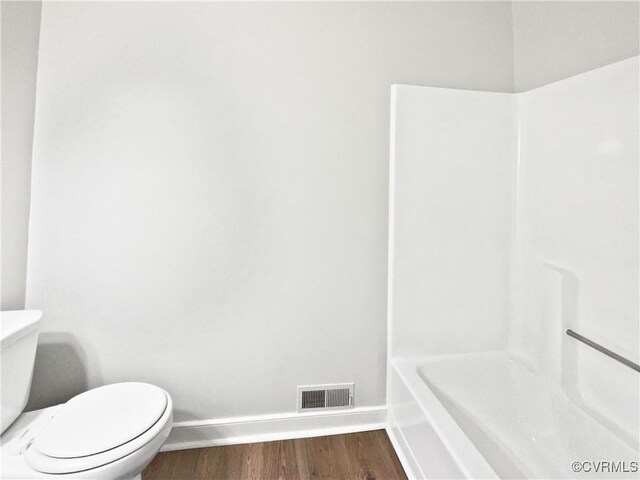bathroom with baseboards, wood finished floors, toilet, a shower, and a bathtub