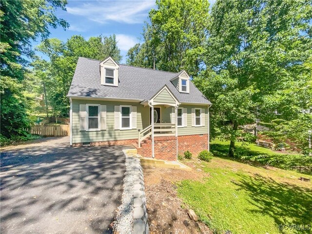 cape cod-style house with driveway and a shingled roof