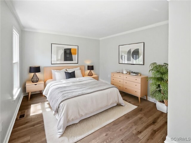 bedroom featuring ornamental molding, baseboards, and wood finished floors