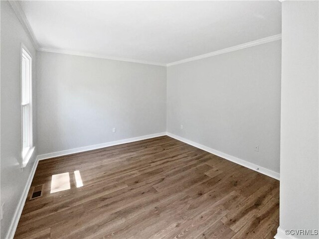 unfurnished room featuring crown molding, dark wood finished floors, and baseboards
