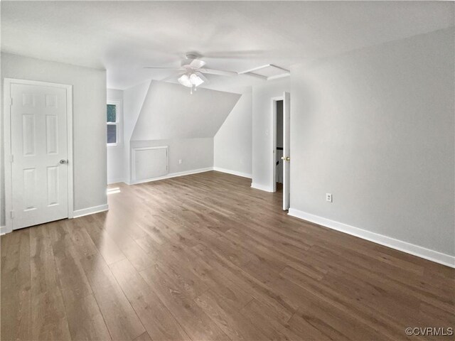additional living space featuring dark wood-style flooring, baseboards, vaulted ceiling, and ceiling fan