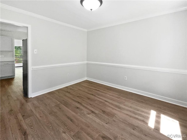 spare room with ornamental molding, dark wood-type flooring, and baseboards