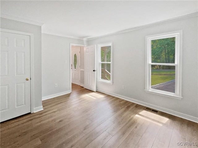 spare room with crown molding, wood finished floors, and baseboards