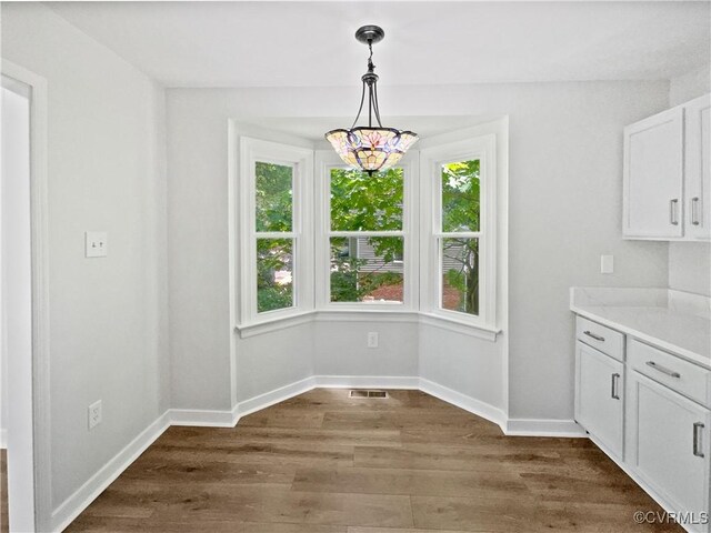 unfurnished dining area with dark wood finished floors and baseboards
