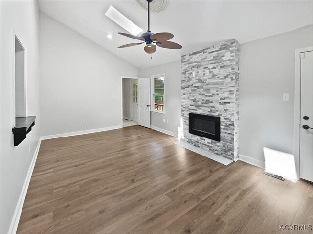unfurnished living room with a ceiling fan, vaulted ceiling, a fireplace, wood finished floors, and baseboards