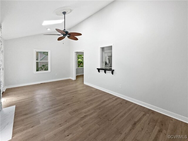unfurnished living room with vaulted ceiling, a ceiling fan, baseboards, and wood finished floors