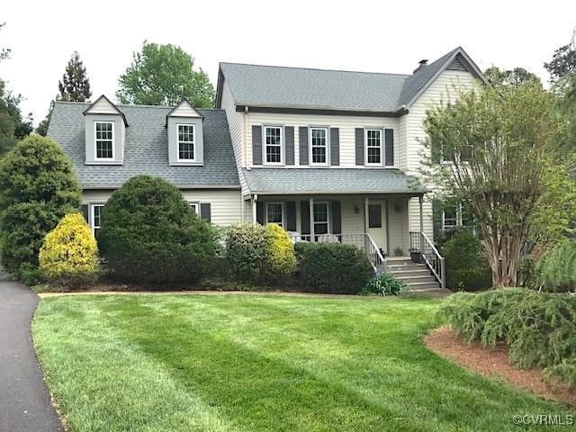view of front of house with covered porch, a front yard, and roof with shingles