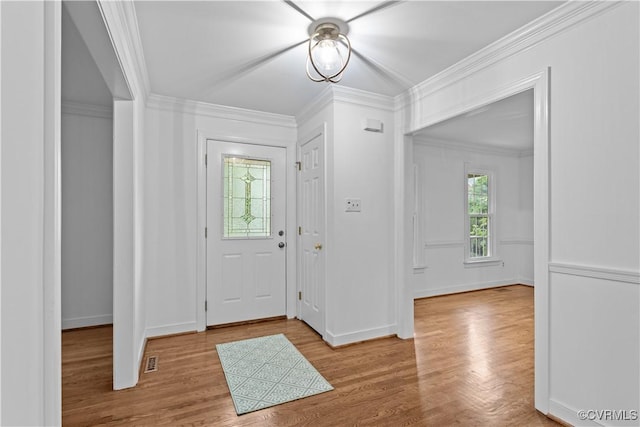 foyer featuring wood finished floors, ornamental molding, and baseboards