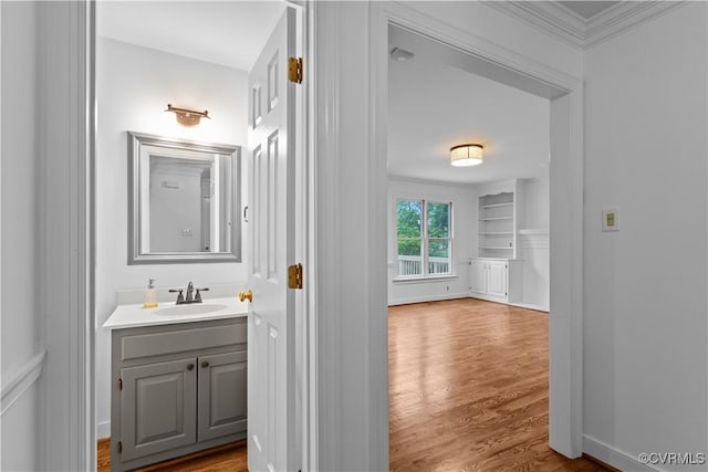 bathroom featuring ornamental molding, wood finished floors, and vanity