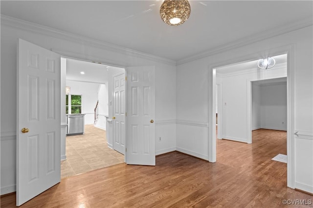 spare room with crown molding, light wood-type flooring, and baseboards