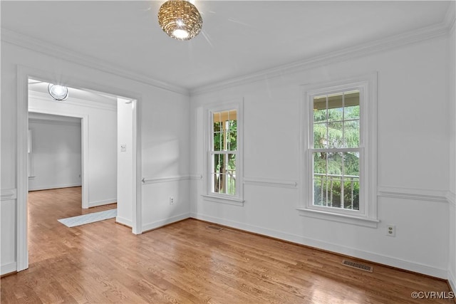 unfurnished room with ornamental molding, light wood-style flooring, and baseboards
