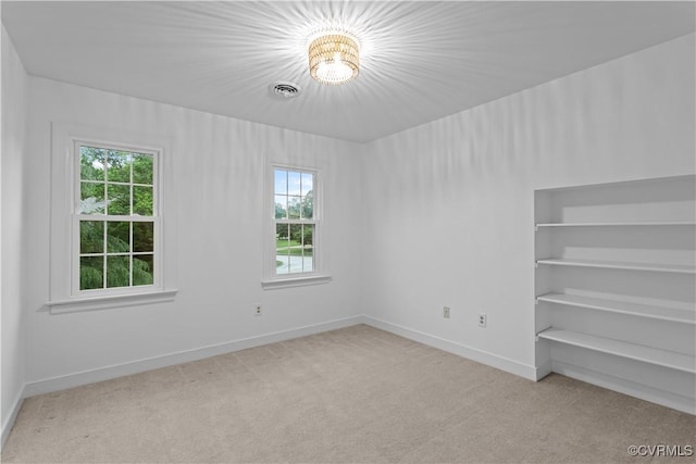 spare room featuring light colored carpet, plenty of natural light, and baseboards