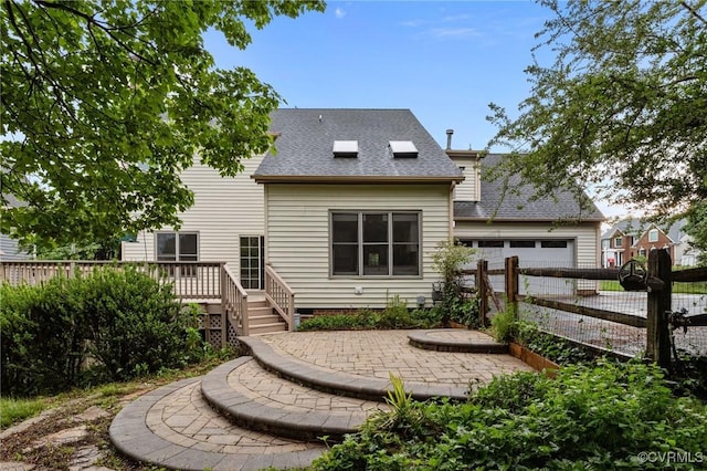 back of property with a shingled roof, fence, a wooden deck, and an attached garage