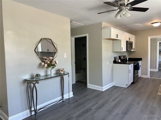 kitchen with appliances with stainless steel finishes, dark countertops, white cabinets, and dark wood-type flooring