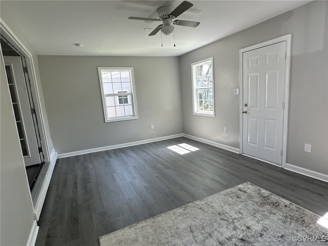 spare room with healthy amount of natural light, dark wood-type flooring, a ceiling fan, and baseboards