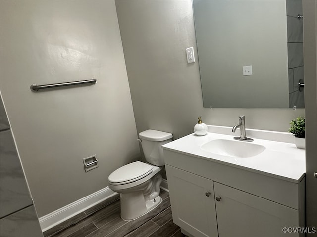 bathroom with baseboards, wood finished floors, vanity, and toilet