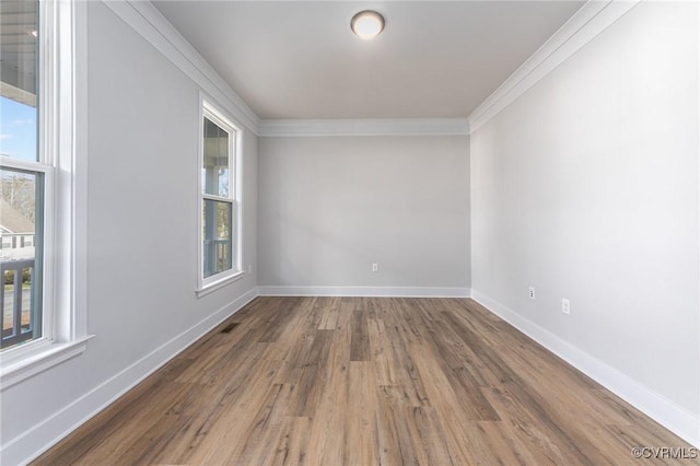 spare room with crown molding, wood finished floors, and baseboards