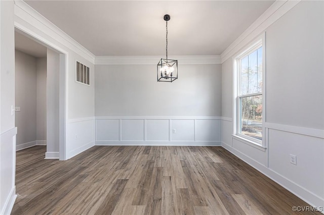 unfurnished dining area featuring wood finished floors, a chandelier, and ornamental molding