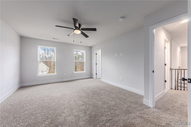 empty room featuring a ceiling fan, carpet, baseboards, and a smoke detector