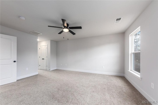 spare room with light carpet, a smoke detector, ceiling fan, and baseboards