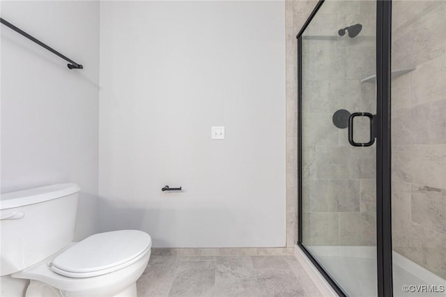 bathroom with a shower stall, toilet, and baseboards