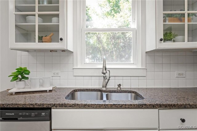 kitchen featuring stainless steel dishwasher, a sink, white cabinets, and glass insert cabinets