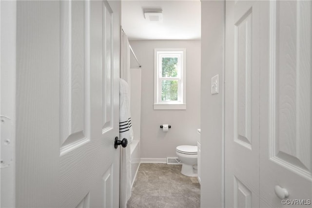 bathroom with toilet,  shower combination, and baseboards