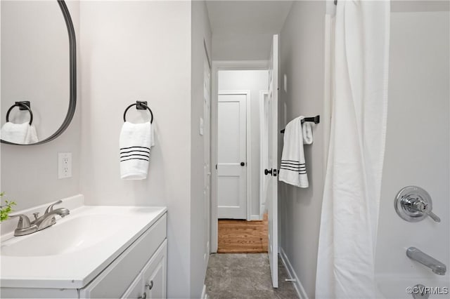 full bath featuring vanity, shower / tub combo, and baseboards