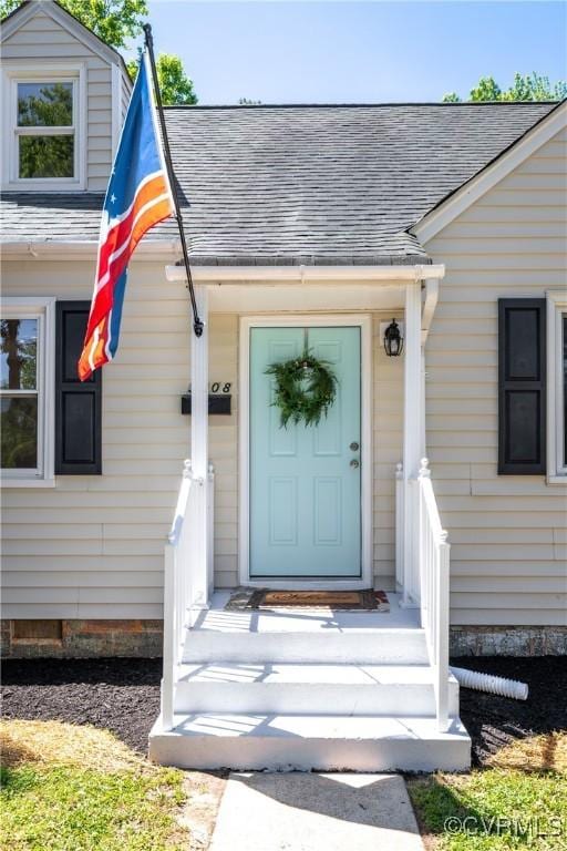 view of exterior entry featuring a shingled roof