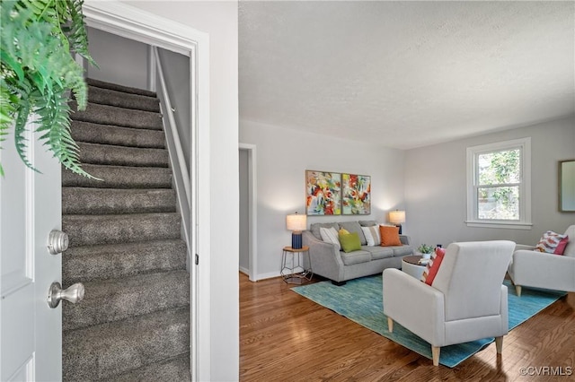living area featuring stairs, wood finished floors, and baseboards
