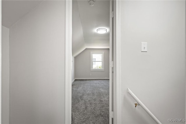 corridor with carpet flooring, vaulted ceiling, and baseboards