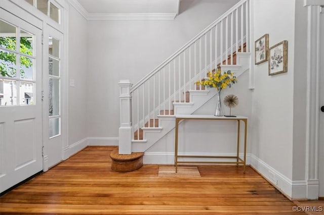 entrance foyer featuring wood finished floors, ornamental molding, stairway, and baseboards